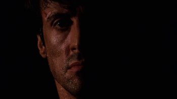 Movie still from “Cobra” (1986), directed by George P. Cosmatos – A man's face in the dark; Close Up shot, Low angle