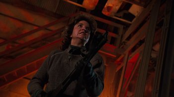 Movie still from “Cobra” (1986), directed by George P. Cosmatos – A person holding a wrench in a room; Medium shot, Low angle