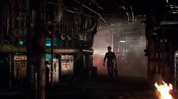 Movie still from “Cobra” (1986), directed by George P. Cosmatos – A man walking through a dark industrial setting; Wide shot, Low angle
