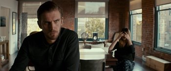 Movie still from “Colossal” (2016), directed by Nacho Vigalondo – A man and a woman sitting at a table in front of a window; Medium shot, Over the shoulder angle