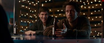 Movie still from “Colossal” (2016), directed by Nacho Vigalondo – Two men sitting at a table with a bottle of beer; Medium shot, Over the shoulder angle