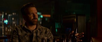 Movie still from “Colossal” (2016), directed by Nacho Vigalondo – A man sitting at a table in front of bottles; Close Up shot, Over the shoulder angle