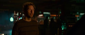 Movie still from “Colossal” (2016), directed by Nacho Vigalondo – A man standing in a dark room at night; Close Up shot, Over the shoulder angle