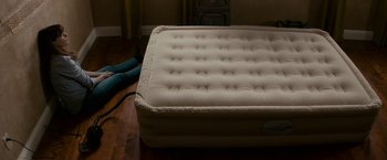 Movie still from “Colossal” (2016), directed by Nacho Vigalondo – An air mattress on the floor of a bedroom; Wide shot, Overhead angle