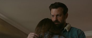 Movie still from “Colossal” (2016), directed by Nacho Vigalondo – A man and a woman hugging each other in a room; Close Up shot, Over the shoulder angle