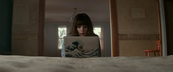 Movie still from “Colossal” (2016), directed by Nacho Vigalondo – A woman sitting in front of an open laptop computer; Medium shot, High angle