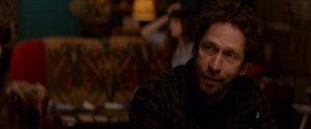 Movie still from “Colossal” (2016), directed by Nacho Vigalondo – A person sitting at a table; Close Up shot, Over the shoulder angle