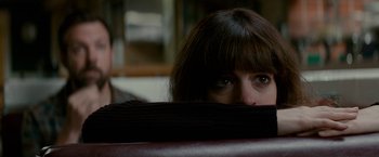 Movie still from “Colossal” (2016), directed by Nacho Vigalondo – A person's face behind a chair; Close Up shot, Over the shoulder angle