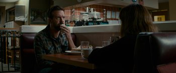 Movie still from “Colossal” (2016), directed by Nacho Vigalondo – A man and a woman sitting at a table; Medium shot, Over the shoulder angle