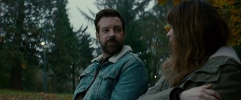 Movie still from “Colossal” (2016), directed by Nacho Vigalondo – A man with a beard is sitting next to a woman; Close Up shot, Over the shoulder angle