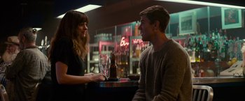 Movie still from “Colossal” (2016), directed by Nacho Vigalondo – A man and a woman sitting at a table with a beer; Medium shot, Over the shoulder angle