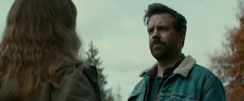 Movie still from “Colossal” (2016), directed by Nacho Vigalondo – A man and a woman standing next to each other in front of trees; Close Up shot, Over the shoulder angle