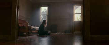Movie still from “Colossal” (2016), directed by Nacho Vigalondo – A woman sitting on the floor of a room; Wide shot, High angle