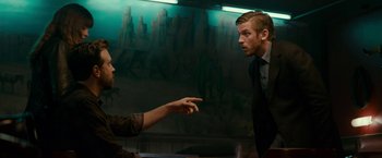Movie still from “Colossal” (2016), directed by Nacho Vigalondo – A man in a suit and tie talking to another man in a suit and tie; Medium shot, Over the shoulder angle