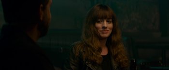 Movie still from “Colossal” (2016), directed by Nacho Vigalondo – A woman in a leather jacket is smiling for the camera; Close Up shot, Over the shoulder angle