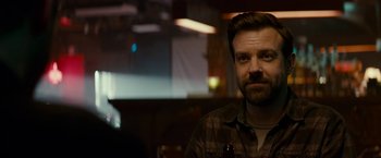 Movie still from “Colossal” (2016), directed by Nacho Vigalondo – A man with a beard is sitting at a table; Close Up shot, Over the shoulder angle