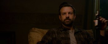 Movie still from “Colossal” (2016), directed by Nacho Vigalondo – A man sitting on a couch in the dark; Close Up shot, Over the shoulder angle