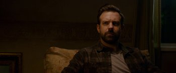 Movie still from “Colossal” (2016), directed by Nacho Vigalondo – A person sitting on a couch; Close Up shot, Over the shoulder angle