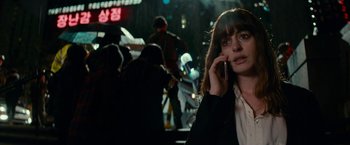 Movie still from “Colossal” (2016), directed by Nacho Vigalondo – A woman talking on a cell phone while standing on a street; Close Up shot, Over the shoulder angle