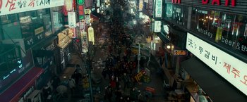 Movie still from “Colossal” (2016), directed by Nacho Vigalondo – A group of people walking down a street at night; Extreme Wide shot, Overhead angle