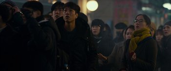 Movie still from “Colossal” (2016), directed by Nacho Vigalondo – A group of people standing in the street at night; Medium shot, Over the shoulder angle
