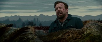 Movie still from “Colossal” (2016), directed by Nacho Vigalondo – A man in a field with his head in the ground; Close Up shot, Low angle