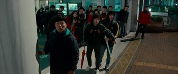 Movie still from “Colossal” (2016), directed by Nacho Vigalondo – A group of people waiting on a train platform; Wide shot, High angle