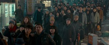 Movie still from “Colossal” (2016), directed by Nacho Vigalondo – A group of people walking down a street; Wide shot, High angle