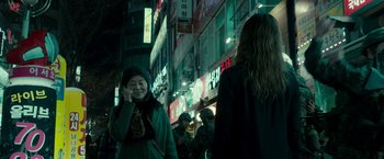 Movie still from “Colossal” (2016), directed by Nacho Vigalondo – A woman talking on a cell phone while standing on the street; Medium shot, Over the shoulder angle