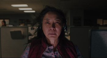 An older woman wearing headphones in an office setting
