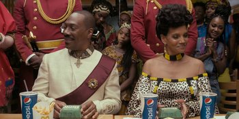 Movie still from “Coming 2 America” (2021), directed by Craig Brewer – A man and a woman sitting next to each other at a table; Medium shot, Over the shoulder angle