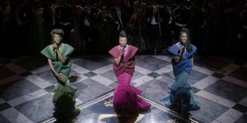 Movie still from “Coming 2 America” (2021), directed by Craig Brewer – A group of women in colorful dresses on a stage; Extreme Wide shot, Low angle