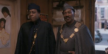 Movie still from “Coming 2 America” (2021), directed by Craig Brewer – A couple of men standing next to each other; Medium shot, Low angle