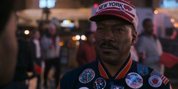 Movie still from “Coming 2 America” (2021), directed by Craig Brewer – A person wearing a hat; Close Up shot, Over the shoulder angle