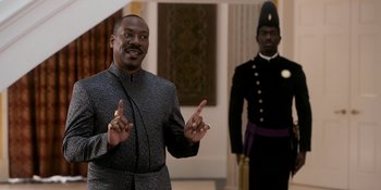 Movie still from “Coming 2 America” (2021), directed by Craig Brewer – A man standing next to another man in a uniform; Medium shot, Over the shoulder angle