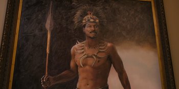 Movie still from “Coming 2 America” (2021), directed by Craig Brewer – A painting of an african man holding a spear; Medium shot, Low angle
