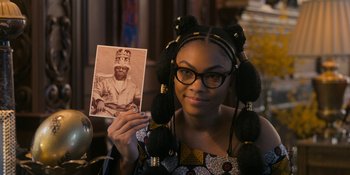 Movie still from “Coming 2 America” (2021), directed by Craig Brewer – A woman holding up an old photo of a man; Close Up shot, Over the shoulder angle