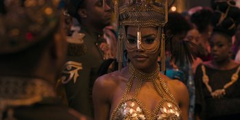 Movie still from “Coming 2 America” (2021), directed by Craig Brewer – A woman in a gold and silver costume and headpiece; Close Up shot, Over the shoulder angle