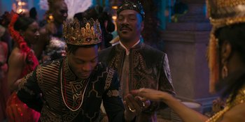 Movie still from “Coming 2 America” (2021), directed by Craig Brewer – Two men in traditional african clothing are looking at a cell phone; Medium shot, Over the shoulder angle