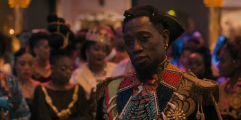 Movie still from “Coming 2 America” (2021), directed by Craig Brewer – A man with a beard and a colorful outfit; Close Up shot, Over the shoulder angle