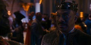 Movie still from “Coming 2 America” (2021), directed by Craig Brewer – A man wearing a crown in front of a group of people; Close Up shot, Over the shoulder angle
