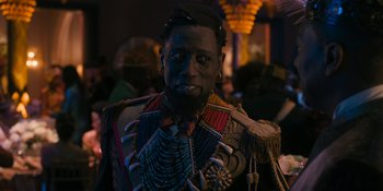 Movie still from “Coming 2 America” (2021), directed by Craig Brewer – A man in a costume is posing for a picture; Close Up shot, Over the shoulder angle