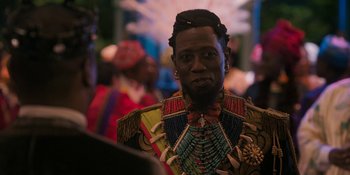 Movie still from “Coming 2 America” (2021), directed by Craig Brewer – A man wearing a colorful outfit with a shell necklace; Close Up shot, Over the shoulder angle