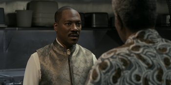 Movie still from “Coming 2 America” (2021), directed by Craig Brewer – A man in a gold vest looking into a mirror; Close Up shot, Over the shoulder angle