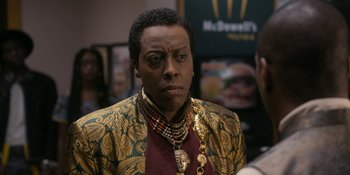 Movie still from “Coming 2 America” (2021), directed by Craig Brewer – A man in a gold and black jacket and a red shirt; Close Up shot, Over the shoulder angle