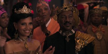 Movie still from “Coming 2 America” (2021), directed by Craig Brewer – A man and woman wearing crowns and holding hands while standing next to each other in front of a crowd; Close Up shot, Over the shoulder angle