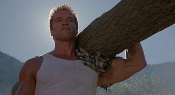 Movie still from “Commando” (1985), directed by Mark L. Lester – A person holding a tree trunk; Close Up shot, Low angle