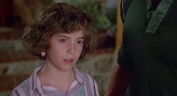 Movie still from “Commando” (1985), directed by Mark L. Lester – A young boy with a curly hair looks at the camera; Close Up shot, Over the shoulder angle