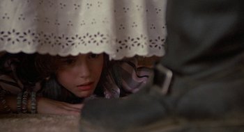 Movie still from “Commando” (1985), directed by Mark L. Lester – A woman hiding under a white curtain; Close Up shot, Low angle