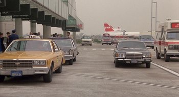 Movie still from “Commando” (1985), directed by Mark L. Lester – Cars are lined up at an airport terminal; Wide shot, Low angle